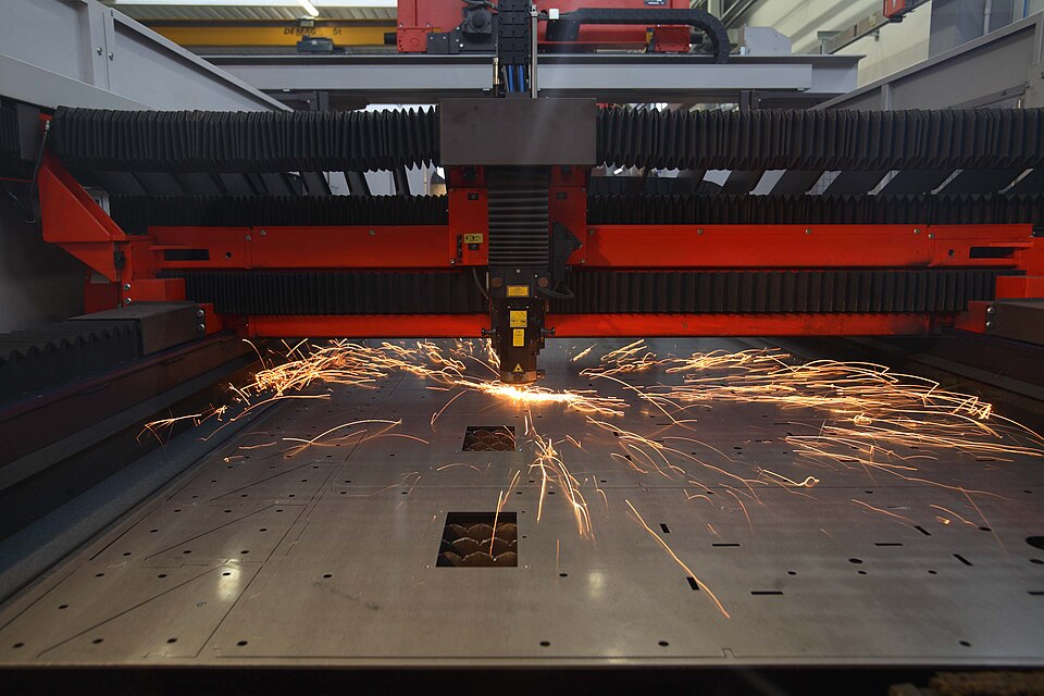 Máquina de corte a laser industrial cortando chapa de aço, com faíscas